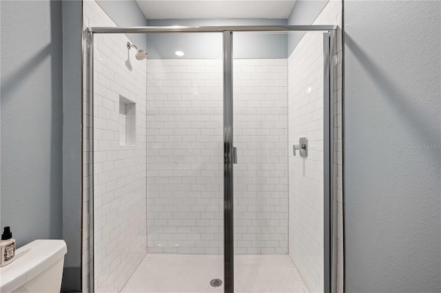 bathroom with toilet and a shower with shower door