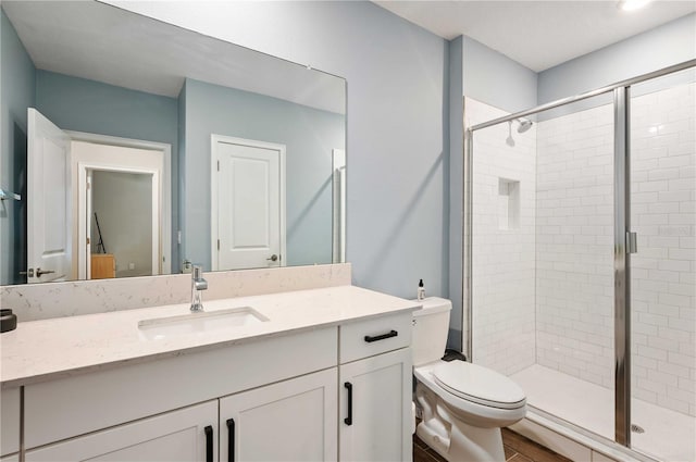 bathroom featuring vanity, toilet, a shower with shower door, and wood-type flooring