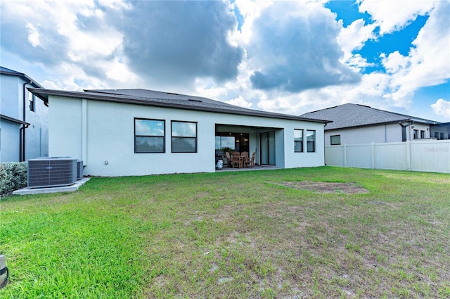 rear view of house with a patio area, central air condition unit, and a yard