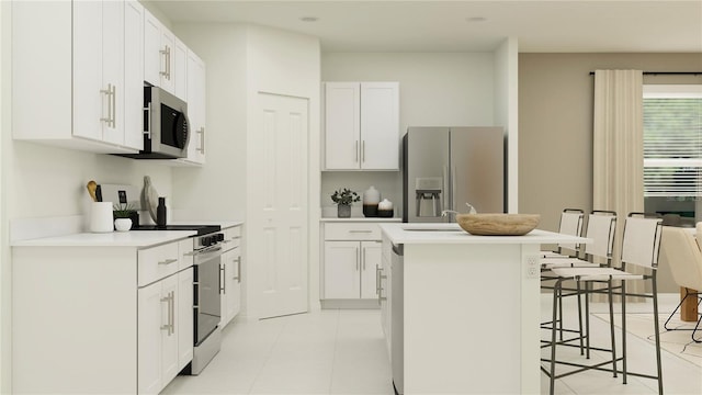 kitchen with white cabinets, light tile patterned floors, an island with sink, appliances with stainless steel finishes, and a breakfast bar area