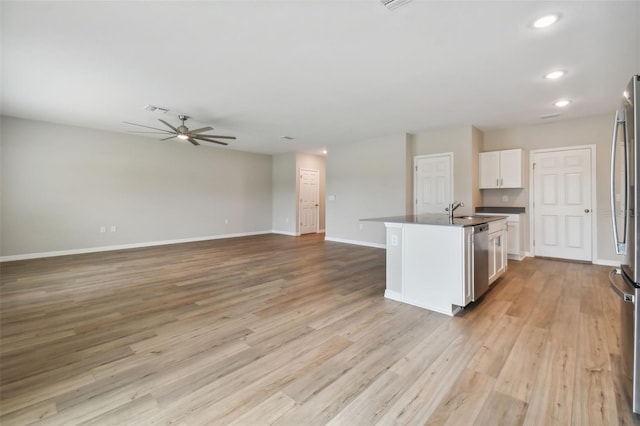 kitchen with ceiling fan, white cabinetry, stainless steel appliances, an island with sink, and light hardwood / wood-style floors