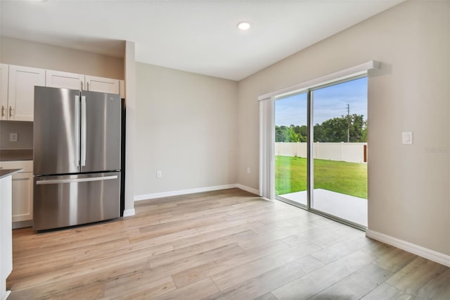 kitchen featuring light wood-type flooring, white cabinetry, and stainless steel refrigerator