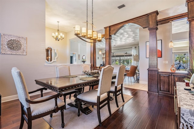 dining area with an inviting chandelier, dark hardwood / wood-style floors, and ornate columns