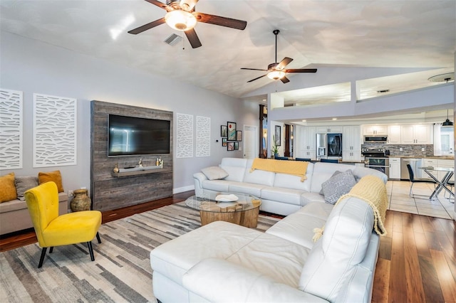 living room with ceiling fan, light hardwood / wood-style flooring, and vaulted ceiling