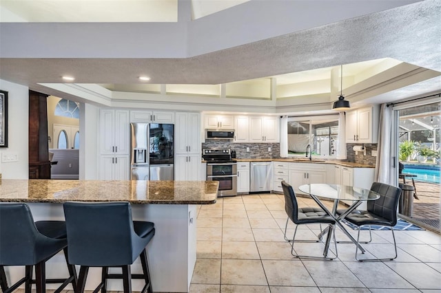 kitchen with sink, white cabinetry, stainless steel appliances, and dark stone counters