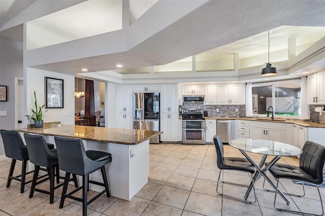 kitchen with white cabinets, a breakfast bar, dark stone countertops, and appliances with stainless steel finishes