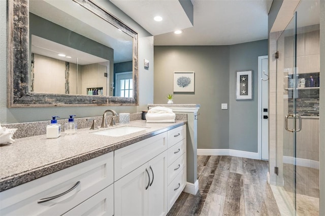 bathroom with hardwood / wood-style floors, vanity, and a shower with door