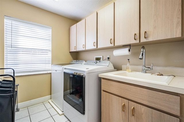 laundry area with cabinets, a textured ceiling, washer and clothes dryer, sink, and light tile patterned floors