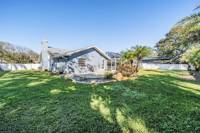 back of house with a patio, a yard, and glass enclosure