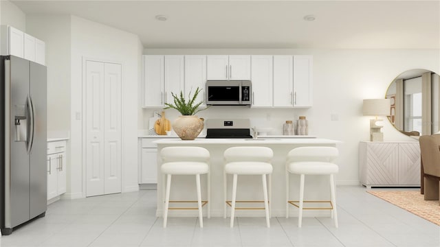 kitchen with white cabinets, light tile patterned floors, a kitchen bar, and stainless steel appliances