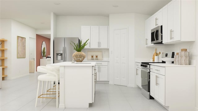 kitchen with a kitchen bar, stainless steel appliances, light tile patterned floors, white cabinetry, and a kitchen island