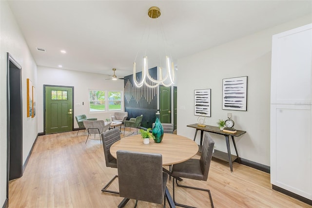 dining space featuring ceiling fan with notable chandelier and light hardwood / wood-style flooring