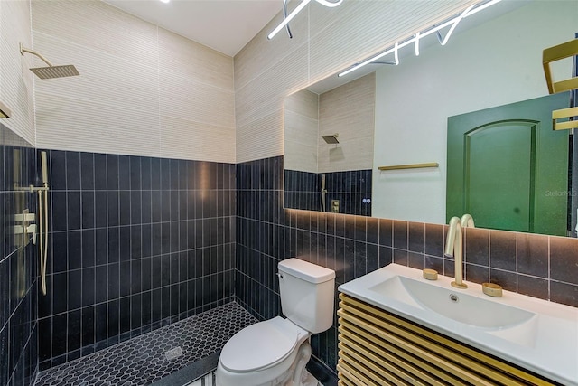 bathroom with toilet, tiled shower, tile walls, backsplash, and vanity