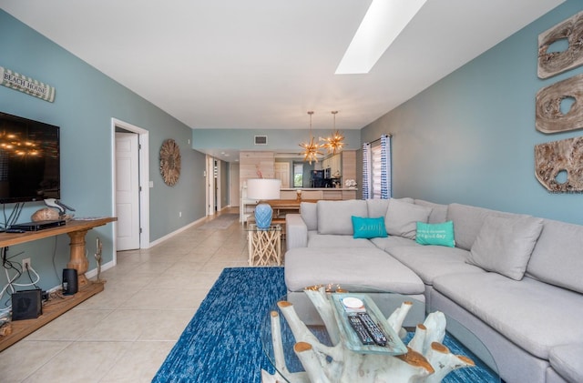 living room featuring a skylight, a notable chandelier, and light tile patterned flooring