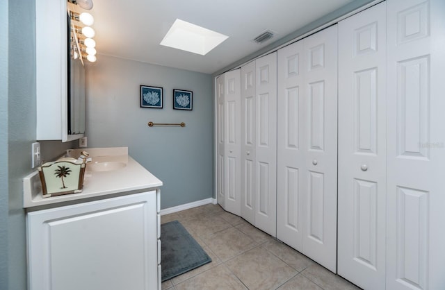 bathroom featuring tile patterned flooring, vanity, and a skylight