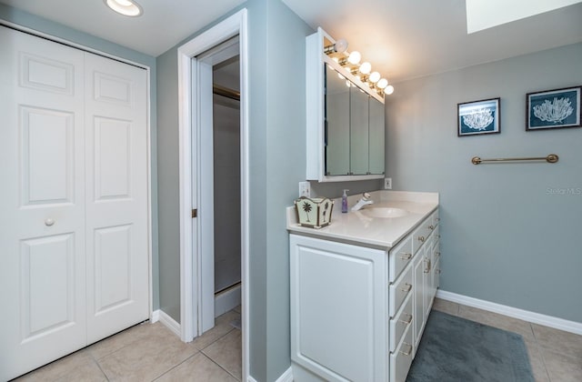 bathroom featuring a skylight, tile patterned flooring, vanity, and walk in shower