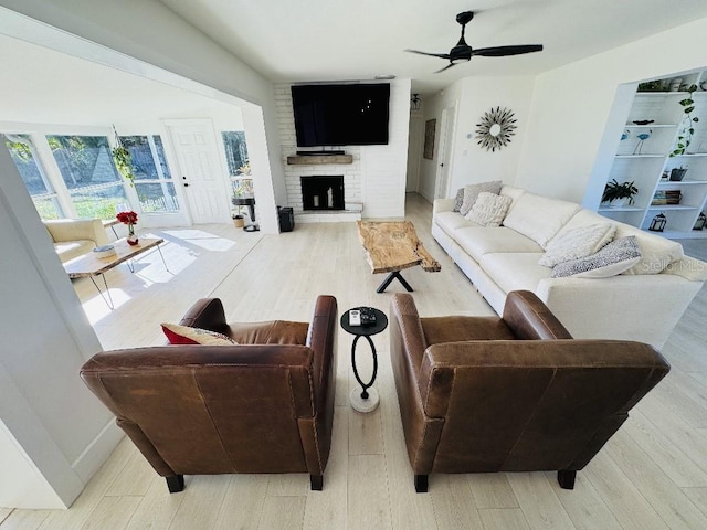 living room with a fireplace, light hardwood / wood-style floors, and ceiling fan