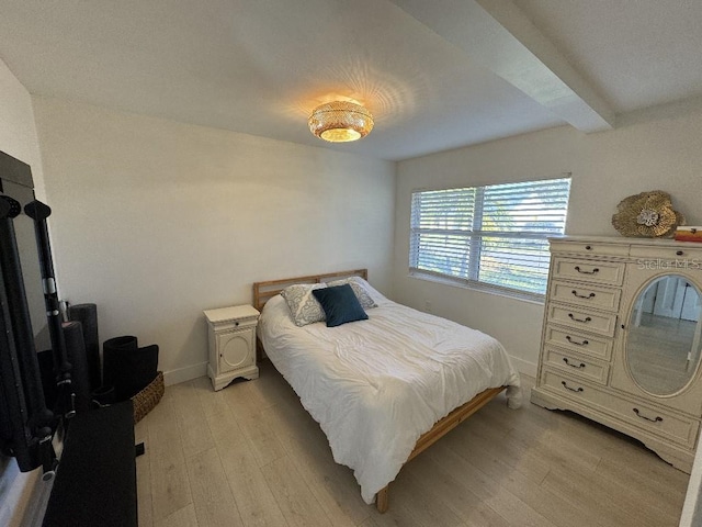 bedroom with beam ceiling and light hardwood / wood-style flooring