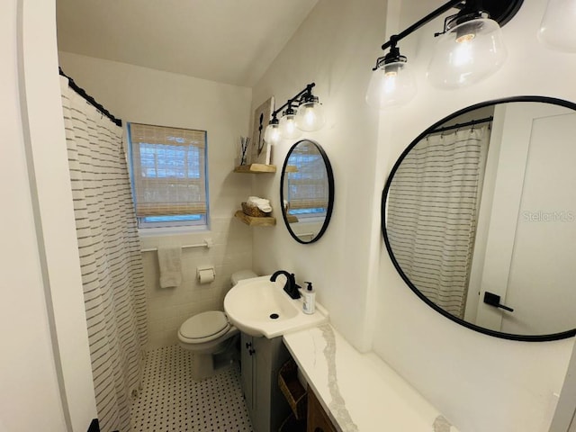 bathroom with vanity, toilet, a shower with shower curtain, and tile walls