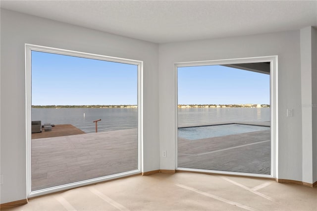 entryway featuring carpet floors, a water view, and a textured ceiling