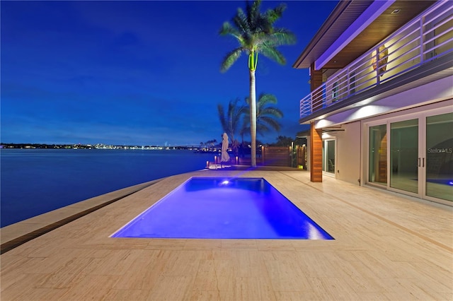 view of pool with french doors, a patio, and a water view