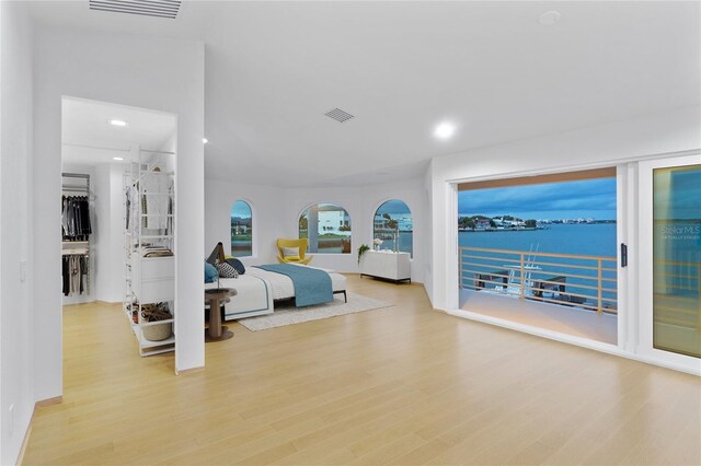 bedroom with access to exterior, light hardwood / wood-style floors, and a water view