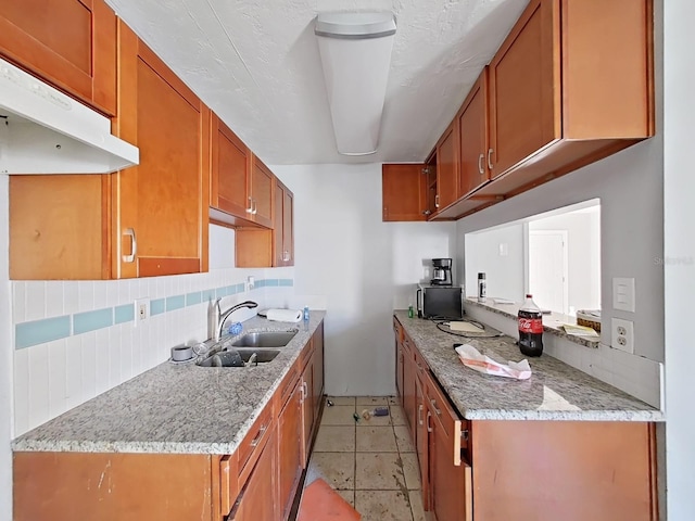 kitchen with decorative backsplash, light stone counters, sink, and light tile patterned floors