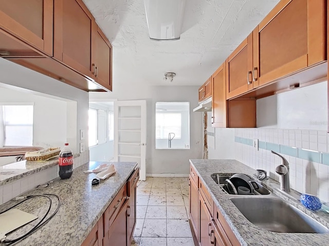 kitchen with light tile patterned flooring, light stone countertops, sink, and tasteful backsplash