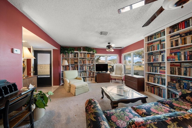 living area featuring carpet flooring, ceiling fan, and a textured ceiling