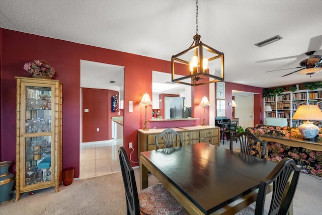 dining space featuring light carpet, a textured ceiling, and ceiling fan with notable chandelier