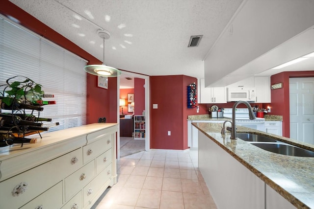 kitchen with sink, light tile patterned floors, a textured ceiling, decorative light fixtures, and white cabinets