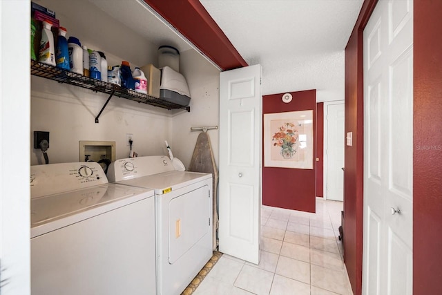 laundry area with washing machine and clothes dryer, light tile patterned flooring, and a textured ceiling