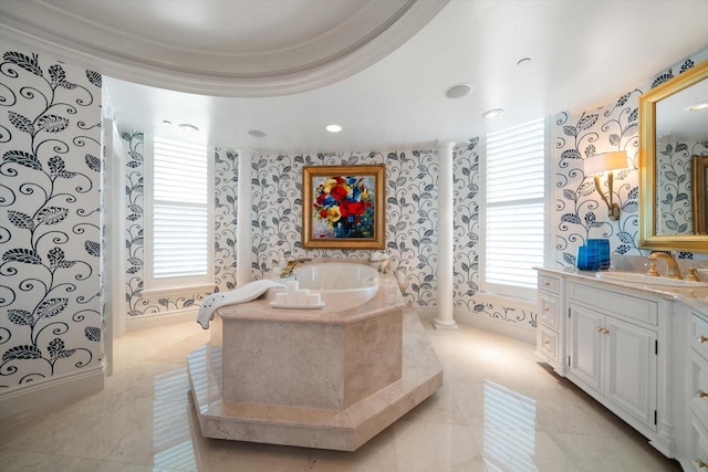 bathroom featuring vanity, ornate columns, and tiled tub