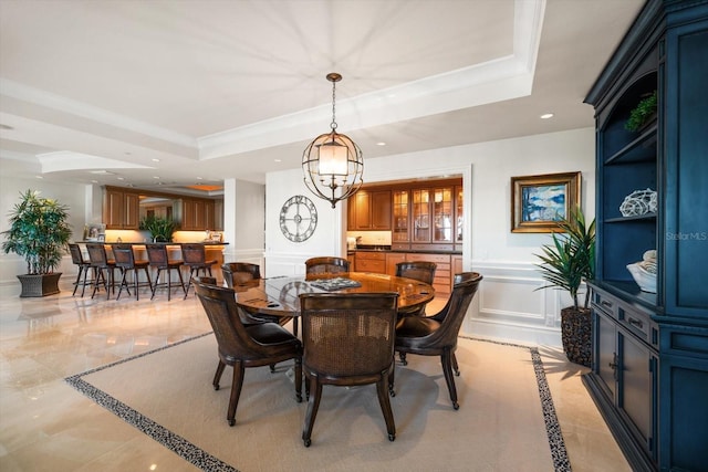 dining space with a raised ceiling, crown molding, and a notable chandelier