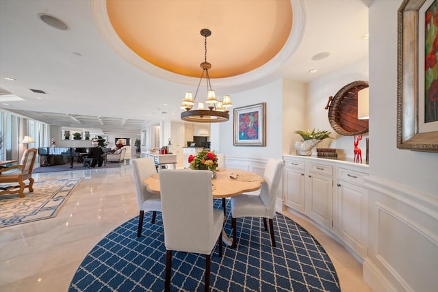 dining area featuring a raised ceiling and a notable chandelier