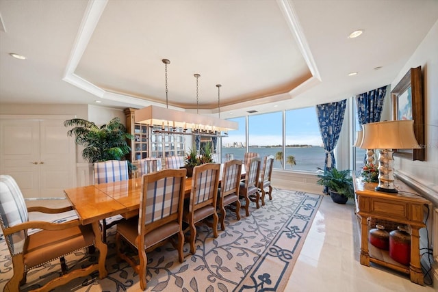 dining room featuring a chandelier, a tray ceiling, a water view, and recessed lighting