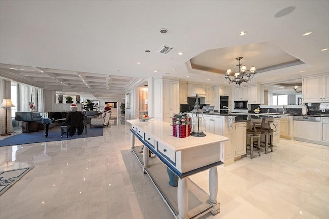 kitchen featuring visible vents, dishwasher, dark countertops, open floor plan, and a tray ceiling