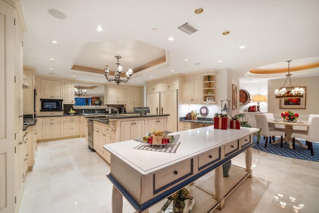 kitchen featuring a chandelier, a raised ceiling, cream cabinets, black microwave, and open shelves