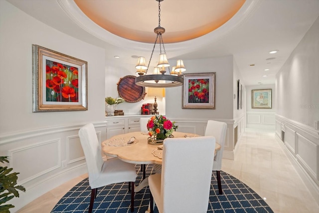 dining room featuring an inviting chandelier, recessed lighting, a decorative wall, and a raised ceiling