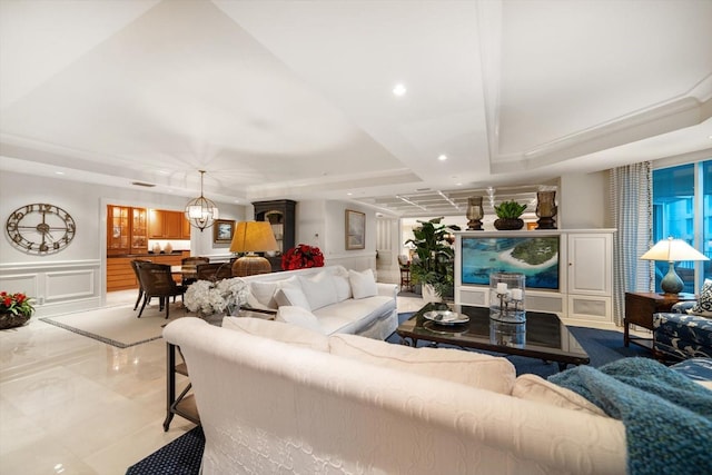 living area featuring recessed lighting, a raised ceiling, a decorative wall, an inviting chandelier, and wainscoting