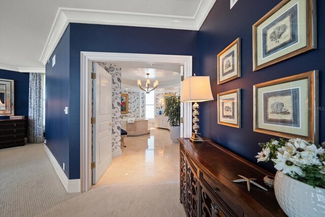 hall with ornamental molding, carpet, a notable chandelier, and baseboards