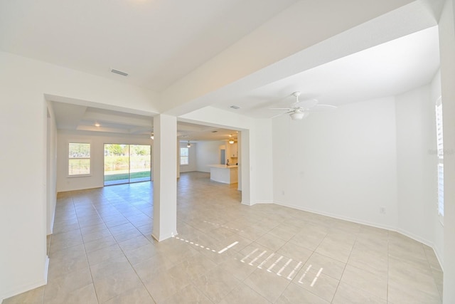 unfurnished room with a tray ceiling, ceiling fan, and light tile patterned floors