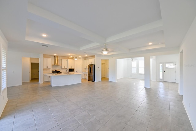 unfurnished living room featuring light tile patterned floors, a tray ceiling, ceiling fan, and sink