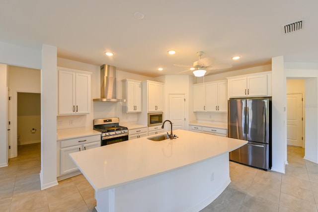 kitchen featuring a center island with sink, wall chimney range hood, sink, white cabinetry, and stainless steel appliances