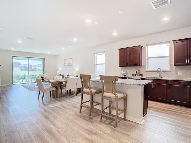 kitchen featuring a center island, light stone counters, sink, and light hardwood / wood-style flooring