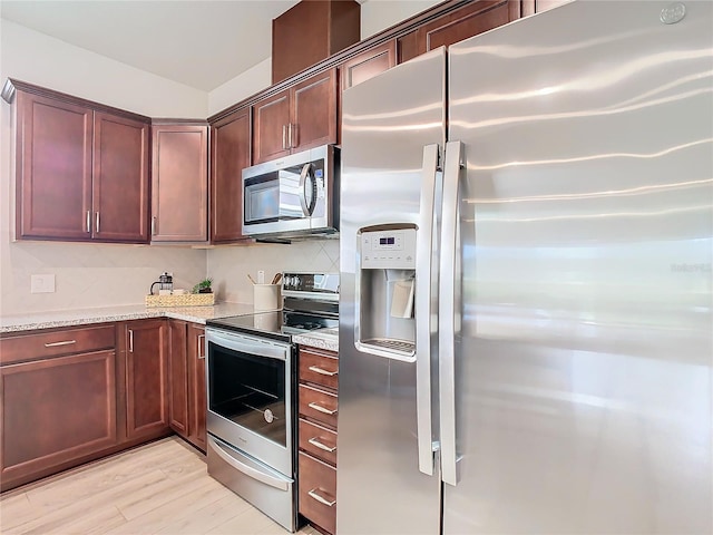 kitchen featuring light stone countertops, appliances with stainless steel finishes, and light hardwood / wood-style floors