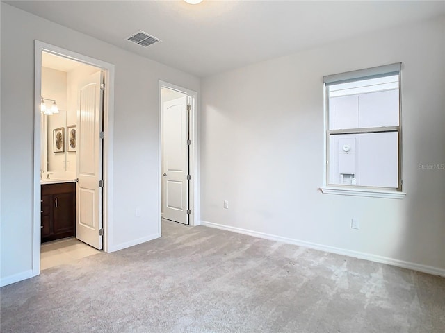 unfurnished bedroom featuring connected bathroom and light colored carpet