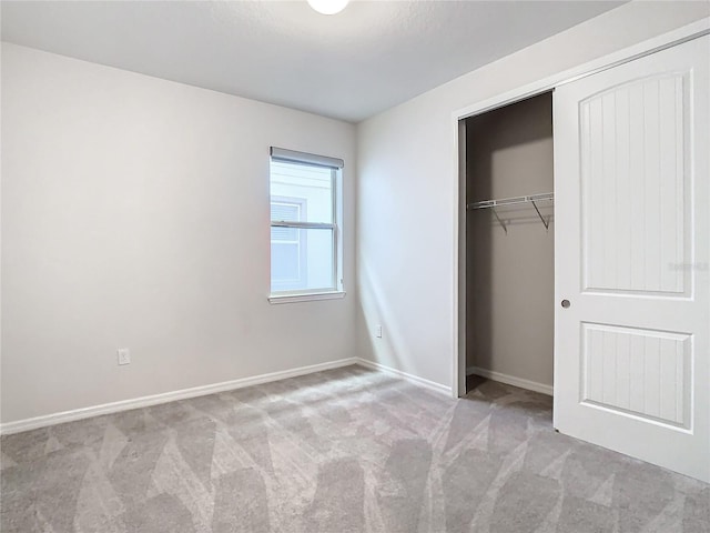 unfurnished bedroom featuring light carpet and a closet