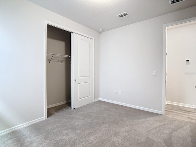 unfurnished bedroom with light carpet and a closet