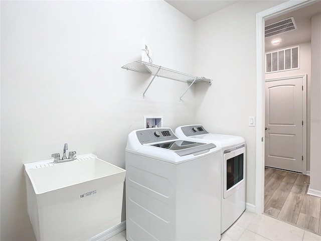 laundry area featuring independent washer and dryer, sink, and light tile patterned floors